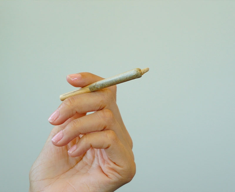 Hand holding cannabis pre-roll